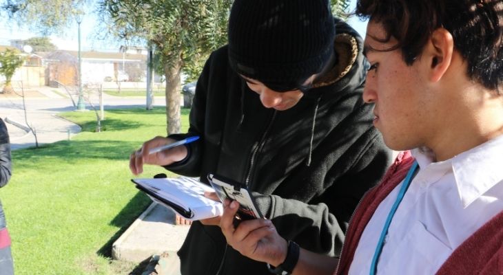 Dos estudiantes de Pablo Malhue haciendo anotaciones durante una clase en el exterior