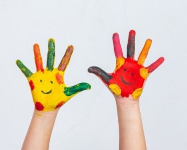 Foto de manos de niño o niña pintadas con caras felices