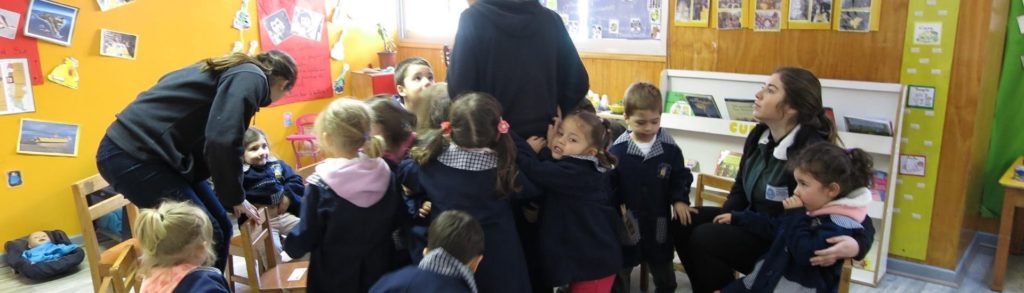 Foto de educadoras junto a niñas y niños que las abrazan