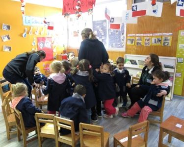 Foto de educadoras junto a niños y niñas en la sala de un jardín infantil