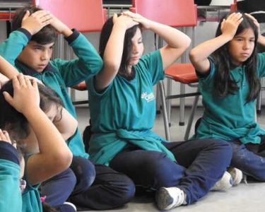 Foto estudiantes participando de una actividad con las manos en la cabeza