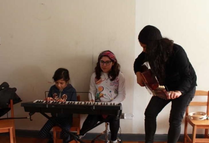 Profesora y estudiantes en el teclado y guitarra