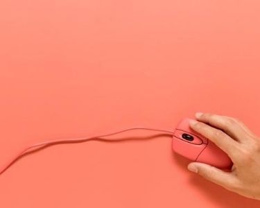 foto de mano sobre mouse con fondo rosa