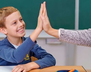Profesora chocando manos con su estudiante