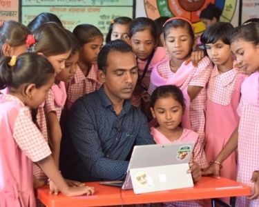 Una fotografía del profesor de la India, Ranjitsinh Disale, trabajando un texto con códigos QR junto a sus alumnas. Crédito: Global Teacher Prize