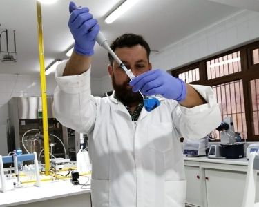 En la imagen se ve al profesor Renzo con instrumentos de Química en sus manos, dentro de un laboratorio