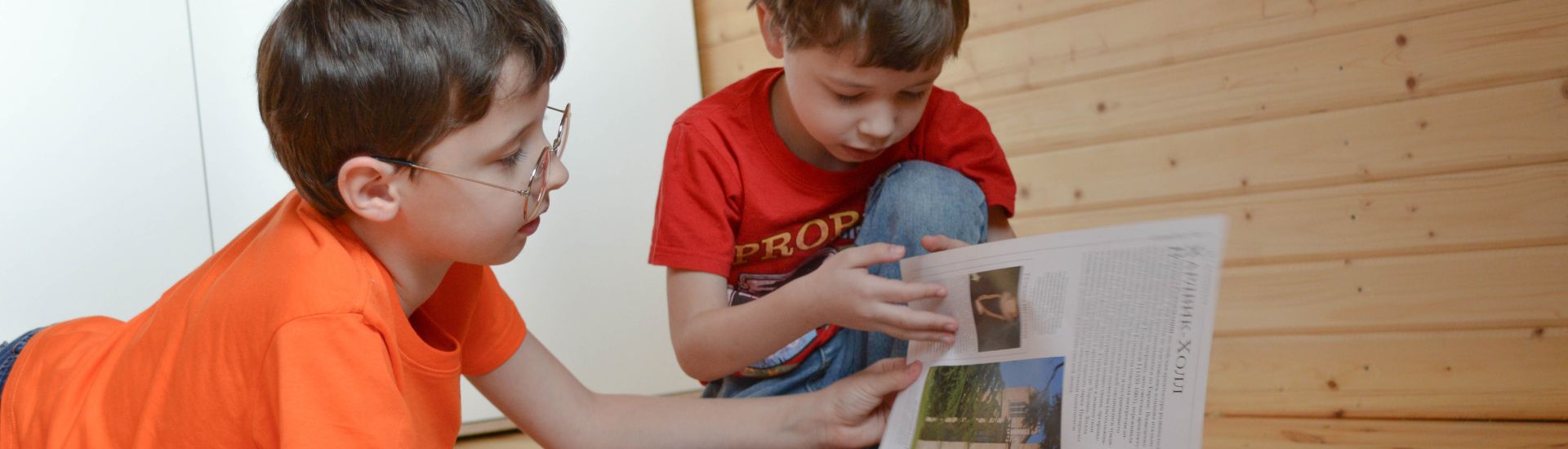 Dos niños leyendo una revista en su casa
