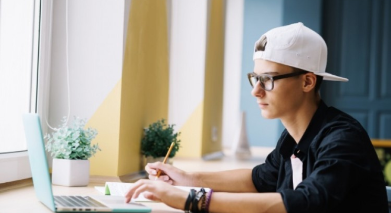 En la fotografía se observa una persona joven frente a un computador.